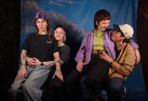 Jezabel sits on Jamie’s lap, who has their arms around Jezabel. Cori sits on Jen’s lap and they share a smile.